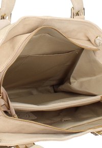 Interno di borsa in camoscio beige con texture liscia, dotata di cerniere dorate, due scomparti e area spaziosa per l'organizzazione.