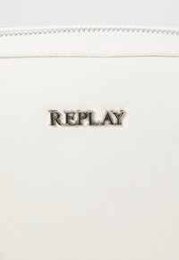 Witte, getextureerde materialen zak met een zilverkleurig metalen 'REPLAY' logo. Ritsluiting aan de bovenkant voegt functionaliteit toe.