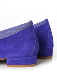 Bailarinas de ante moradas con un pequeño tacón cuadrado, que cuentan con un ribete de tela texturizada a lo largo del borde superior para mayor detalle y contraste.