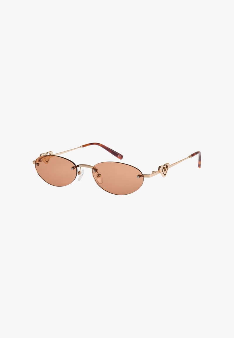 Lunettes de soleil ovales teintées en marron avec des montures fines en or, des plaquettes de nez et des accents en forme de cœur sur les branches, terminées par des embouts en écaille.
