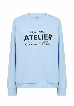 Light blue long-sleeve sweatshirt with round neckline, featuring black text printed: "ATELIER Avenue de Paris" with vintage year 1986.