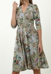 Blumendruckkleid mit V-Ausschnitt, dreiviertellangen Ärmeln, Knöpfen auf der Vorderseite und einem ausgestellt Rock in grünen, rosa und beigen Farbtönen.