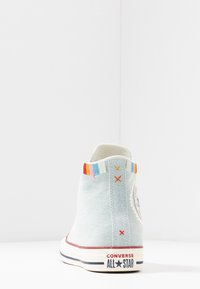 Světle modré plátěné vysoké tenisky s vícebarevnými vyšívanými detaily na límci, bílou gumovou podrážkou a brandingem Converse All Star.