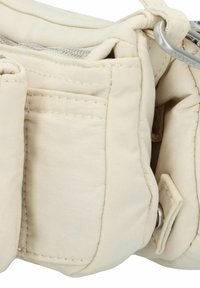 Beige gewatteerde tas met meerdere zakken, zilverkleurige hardware en gestikt detail. Zacht materiaal met een gladde textuur.
