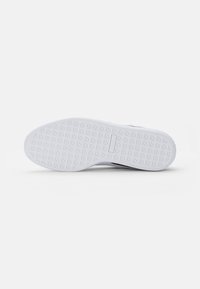 Sola di sneaker bianca con motivo di grip testurizzato, caratterizzata da una finitura liscia e una forma arrotondata, senza marchi visibili o dettagli aggiuntivi.