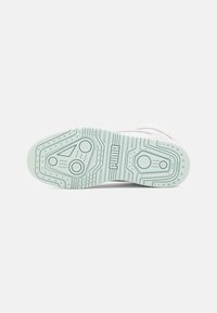 Light green rubber sneaker sole with textured surface, featuring circular patterns and a Puma logo. Designed for traction and durability.