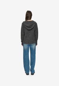 Sudadera de punto gris oscuro con un corte relajado, que presenta una capucha y puños acanalados, combinada con unos jeans de denim sueltos en azul claro.