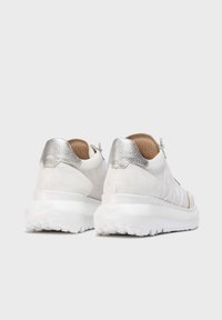 Baskets blanches avec une finition texturée, des accents argentés au niveau du talon, une semelle rembourrée et un design léger adapté à un usage décontracté.