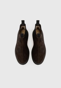 Botas de tobillo de ante marrón con paneles laterales elásticos, suelas de goma planas y lengüetas para facilitar su uso. Interior forrado con material suave.