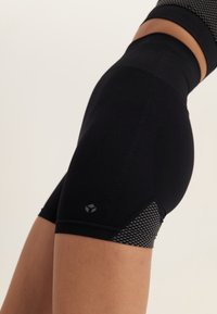 Shorts de sport noirs avec une texture côtelée, dotés d'un panneau en maille sur le côté et d'un petit logo près de l'ourlet.