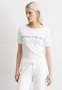 Kortærmet hvid T-shirt med rund halsudskæring, med "Marc O'Polo" trykt i mørkegrå. Blødt, struktureret stof, afslappet pasform.