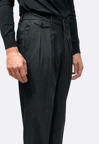 Pantaloni neri in tessuto liscio, caratterizzati da pieghe, tasche laterali con chiusura a bottone e una cintura elasticizzata per il massimo comfort.