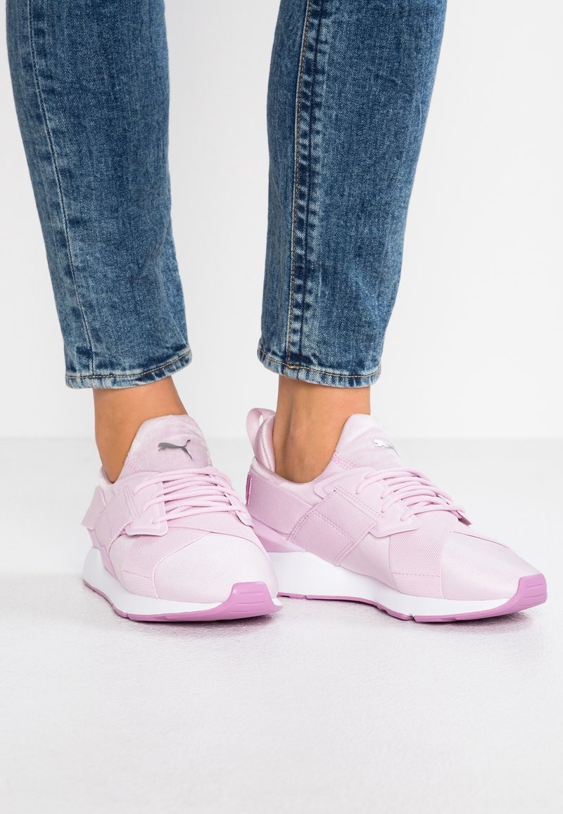 Vaaleanpunaiset urheilukengät, joissa on verkko- ja synteettisiä materiaaleja. Ominaisuuksiin kuuluu pehmustettu kaulus, nauhakiinnitys ja erottuva violetti pohja.