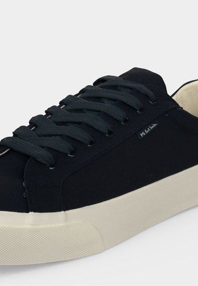 Baskets en toile noire avec semelle épaisse crème claire et lacets noirs, avec une petite étiquette de marque PS Paul Smith sur le côté.