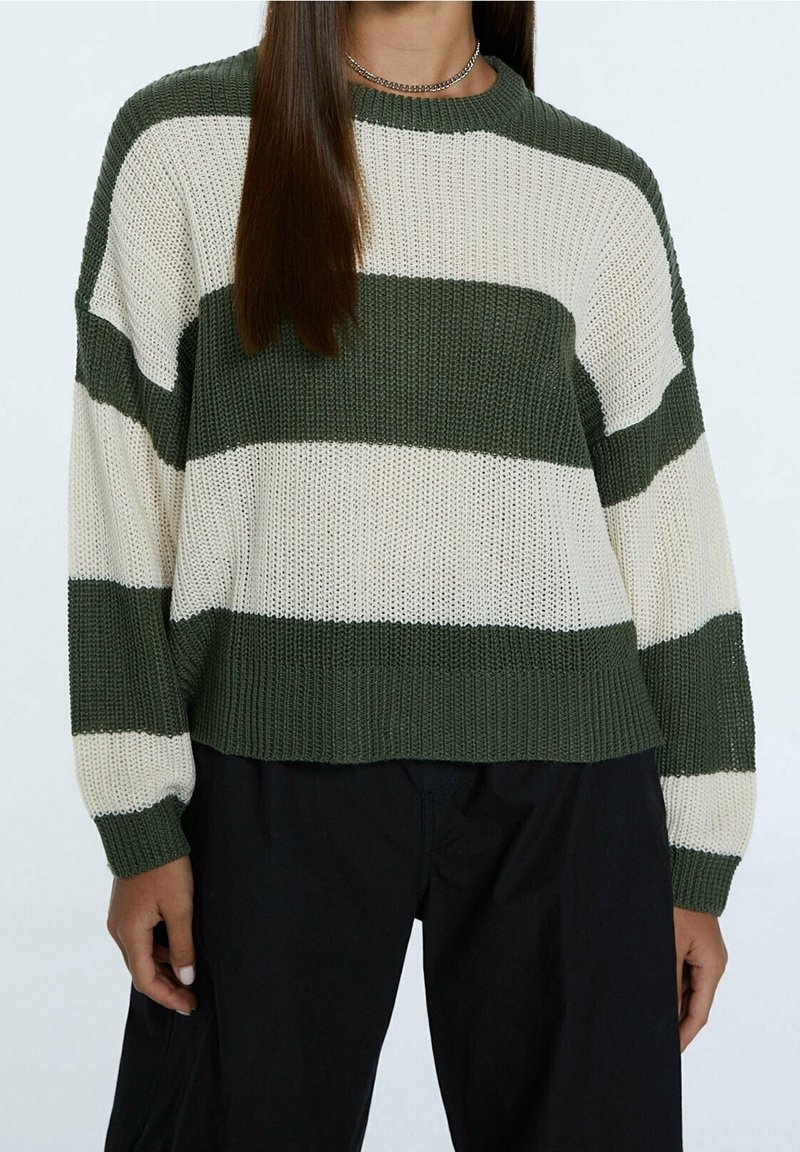 Knitted sweater featuring green and cream horizontal stripes, crew neckline, and ribbed cuffs with a relaxed fit. Fabric appears textured.