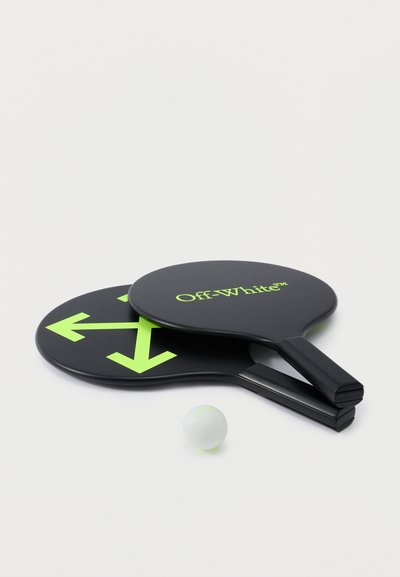 Deux raquettes de tennis de table noires, l'une avec des flèches vert néon, l'autre avec le texte « Off-White », et une balle de ping-pong blanche sur une surface blanche.