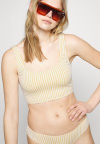 Top de biquíni riscado com decote quadrado, apresentando riscas amarelas sobre um fundo creme, combinado com parte de baixo de biquíni a condizer.