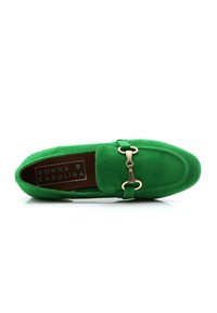 Mocasín de ante verde con puntera redondeada, acentuado por un detalle de herraje en tono dorado con forma de bit de caballo. El interior muestra el nombre de la marca "DONNA CAROLINA."