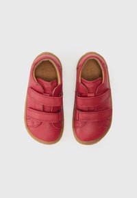 Κόκκινα δερμάτινα παπούτσια με δύο λουράκια με βέλκρο, στρογγυλεμένη μύτη και ανοιχτόκαφέ καουτσούκ σόλα. Υφή με φυσικό φινίρισμα.