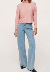 Vaaleanpunainen ribbineulottu pooloneule, lyhyt malli. Yhdistetty vaaleansinisiin leveälahkeisiin farkkuihin, joissa on rispaantunut helma, ja mustiin korollisiin saappaisiin.