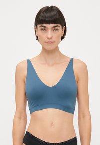 Blauwe, zachte stof bralette met een diepe V-hals, brede banden en een naadloos ontwerp, gecombineerd met zwart ondergoed met kanttrim.