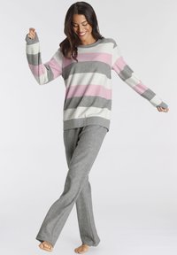 Striped sweater in pink, gray, and white with long sleeves, paired with gray lounge pants. Soft fabric, relaxed fit, no prominent details.