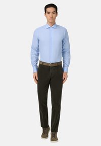 Lichtblauw geruit overhemd met een spread collar, gecombineerd met donkergroene corduroybroek en grijs-brown casual schoenen.