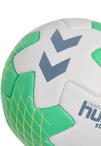 Palla da allenamento per il calcio con una superficie bianca caratterizzata da accenti verdi e un motivo a griglia. Il materiale è probabilmente sintetico, con una finitura testurizzata.