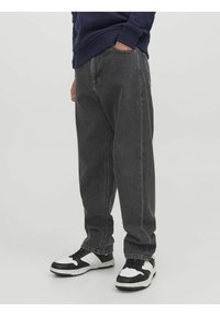 Vaqueros de mezclilla gris oscuro con un corte holgado y recto, y costuras de contraste; combinados con zapatillas en blanco y negro.