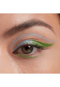 Nära bild av ett öga som har blå och grön ögonskugga med metallisk lyster. Ögonlocket är format med djärva, vinklade linjer.