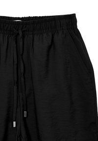 Pantaloni corti neri con vita elasticizzata, cordoncino con estremità in metallo e tasche laterali. Tessuto testurizzato con finitura liscia.