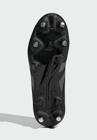 Mustan jalkapallokengän pohja, jossa on kiiltävät hopeiset niitit, teksturoitu muotoilu ja ergonominen muoto. Pohjassa on brändilogo kohokuvioituna.