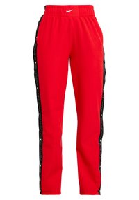 Pantalones deportivos rojos con una franja lateral negra que presenta el texto repetido "NIKE PRO", cintura elástica y textura suave.