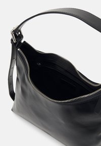 Fekete bőr válltáska ezüst cipzárral, állítható pánttal és látható belső cipzáras zsebbel.