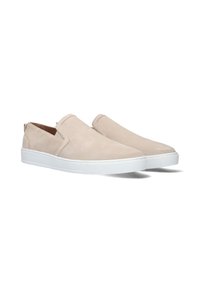 Beige suède instappers met witte rubberen zolen, laag profiel ontwerp en elastische zijpanelen voor gemakkelijk aan- en uittrekken.