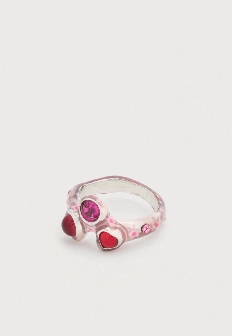 Bague en argent ornée de trois pierres précieuses en forme de cœur aux nuances rouge et rose, avec une finition émaillée rose texturée et translucide.