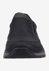 Zapatos de piel negros tipo mocasín con costuras contrastantes, superficie texturizada, un acento gris cerca del talón y una suela de goma flexible.