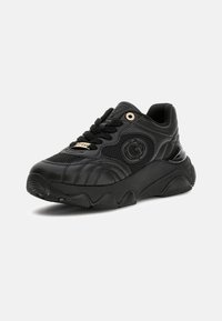 Black chunky sneaker with textured sole, mesh and leather panels, branded eyelet, and lace tag on plain light background.