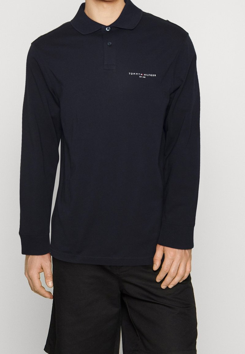 Langarm-Navy-Poloshirt aus Baumwolle, mit klassischem Kragen, zwei-Knopf-Leiste und kleinem weißen Logo auf der Brust.