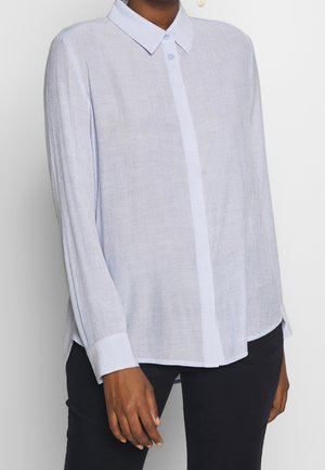 Camicia a maniche lunghe azzurro chiaro con colletto a bottoni, pattina frontale e polsini; realizzata in un tessuto testurizzato e traspirante.