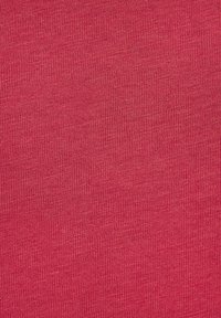 Pletená látka v jednofarebnej jasne ružovej farbe, s hladkou textúrou a jemnými vertikálnymi pruhmi po celej ploche.