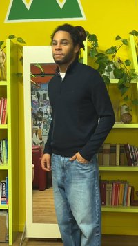 Marineblauwe trui met rits gecombineerd met lichtblauwe spijkerbroek. De trui heeft een geribbelde zoom en manchetten, terwijl de achtergrond een spiegel en planten bevat.