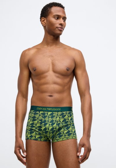 Žalios bokserio kelnaitės su geometriniu geltonų lapų raštu, su elastine juostos, kurioje nurodytas "EMPORIO ARMANI" logotipas žalios spalvos.