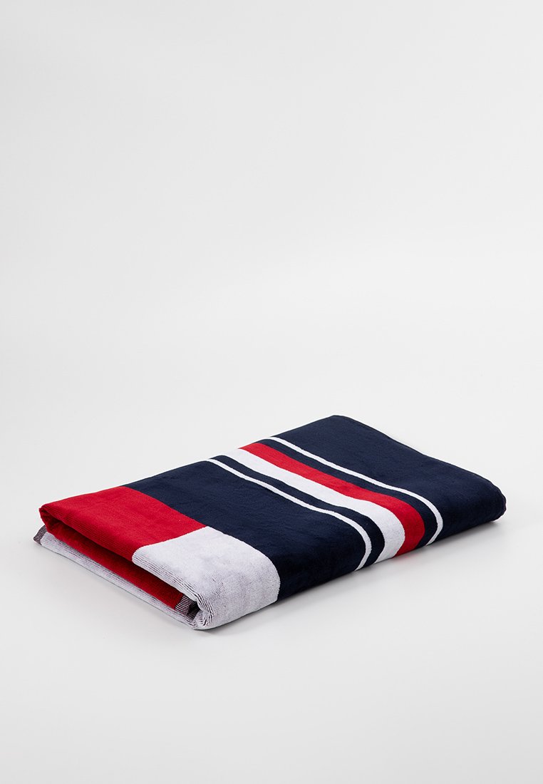 Serviette multicolore avec des rayures bleu marine, rouge et blanche. Texture douce avec une forme rectangulaire pliée, montrant des blocs de couleur contrastés.