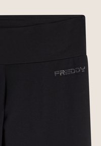 Leggings neri realizzati in materiale morbido, dotati di una vita ampia e di un discreto logo argento "FREDDY" sul lato.