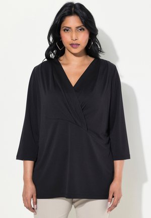 Black pullover top with a V-neck, three-quarter sleeves, and diagonal draping detail. Smooth fabric with a relaxed fit.