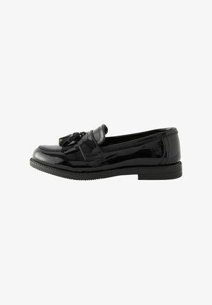 Mocassins en cuir verni noir avec détail de gland, bout arrondi et semelle en caoutchouc à faible contraste, présentant une finition lisse et brillante.