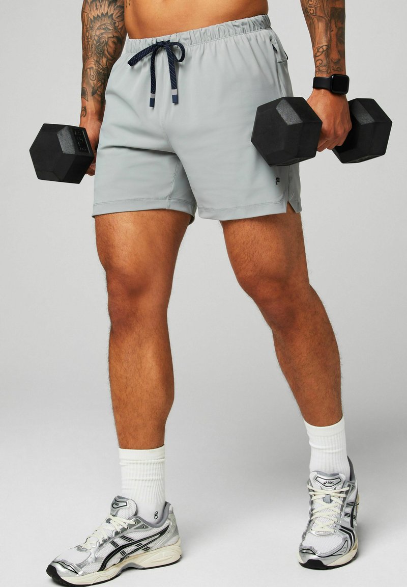 Graue Sportshorts mit elastischem Bund und Kordelzug, kombiniert mit schwarzen sechseckigen Hanteln. Weiße Sportsocken und Laufschuhe.