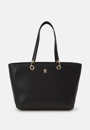 Zwarte leren tote tas met twee handvatten, gouden hardware en een klein metalen logo aan de voorkant in het midden.
