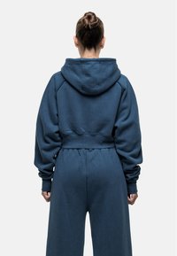 Donkerblauwe cropped hoodie met een ruime capuchon en elastische tailleband, voorzien van lange mouwen met ribgebreide manchetten en een zachte, gestructureerde stof.